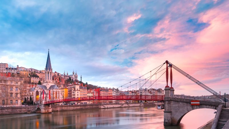 Pont rouge et église à Lyon au coucher du soleil.